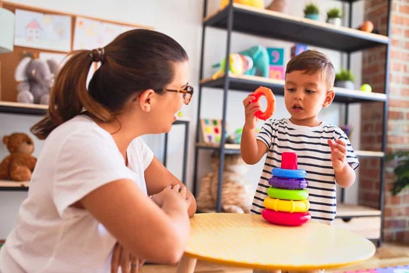 Yürümeye başlayan çocuğun konuşmasına yardımcı olmak için oyuncak kullanan bir kadın