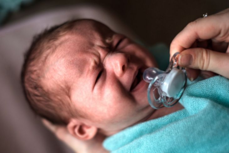 Bambino che piange usando il ciuccio