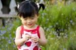 Fată chineză zâmbitoare ținând o floare în mâini